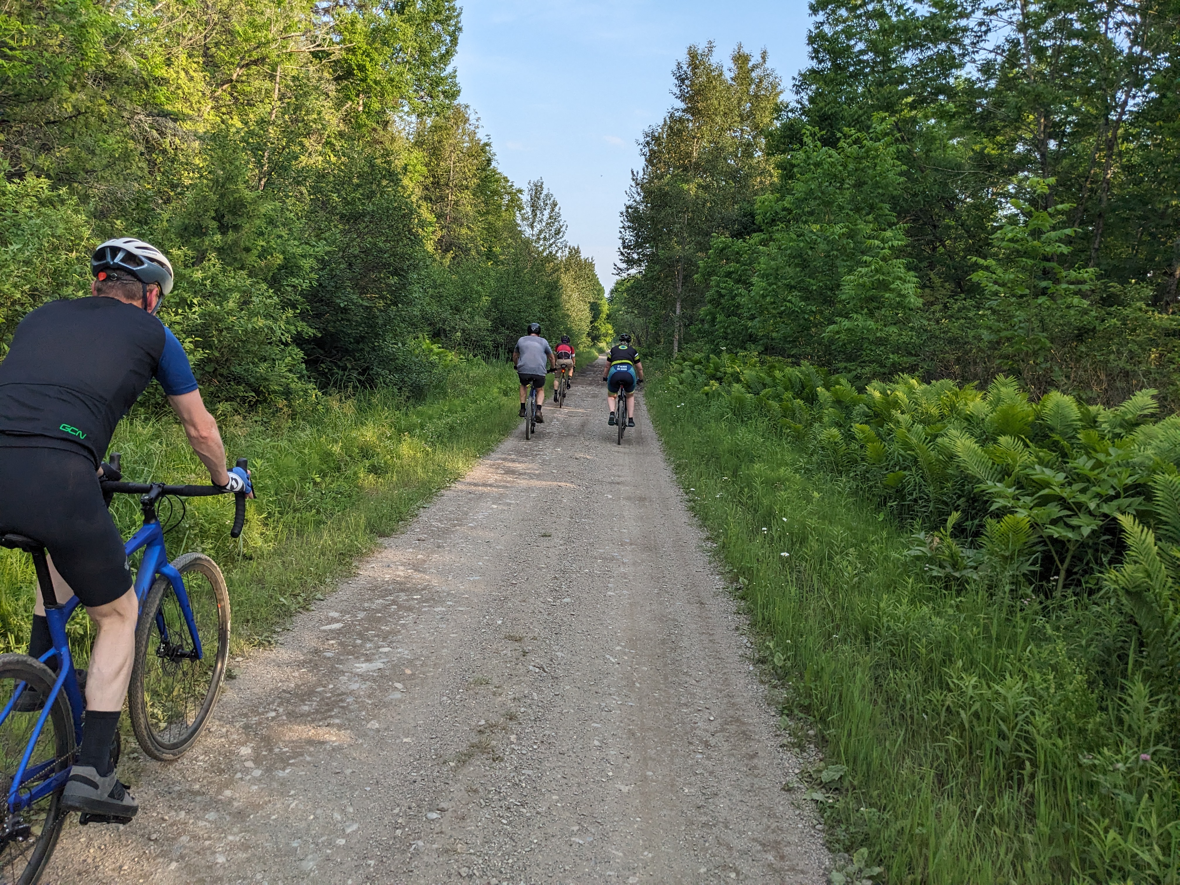 Riders on a gravel trail through the trees in Northern Maine