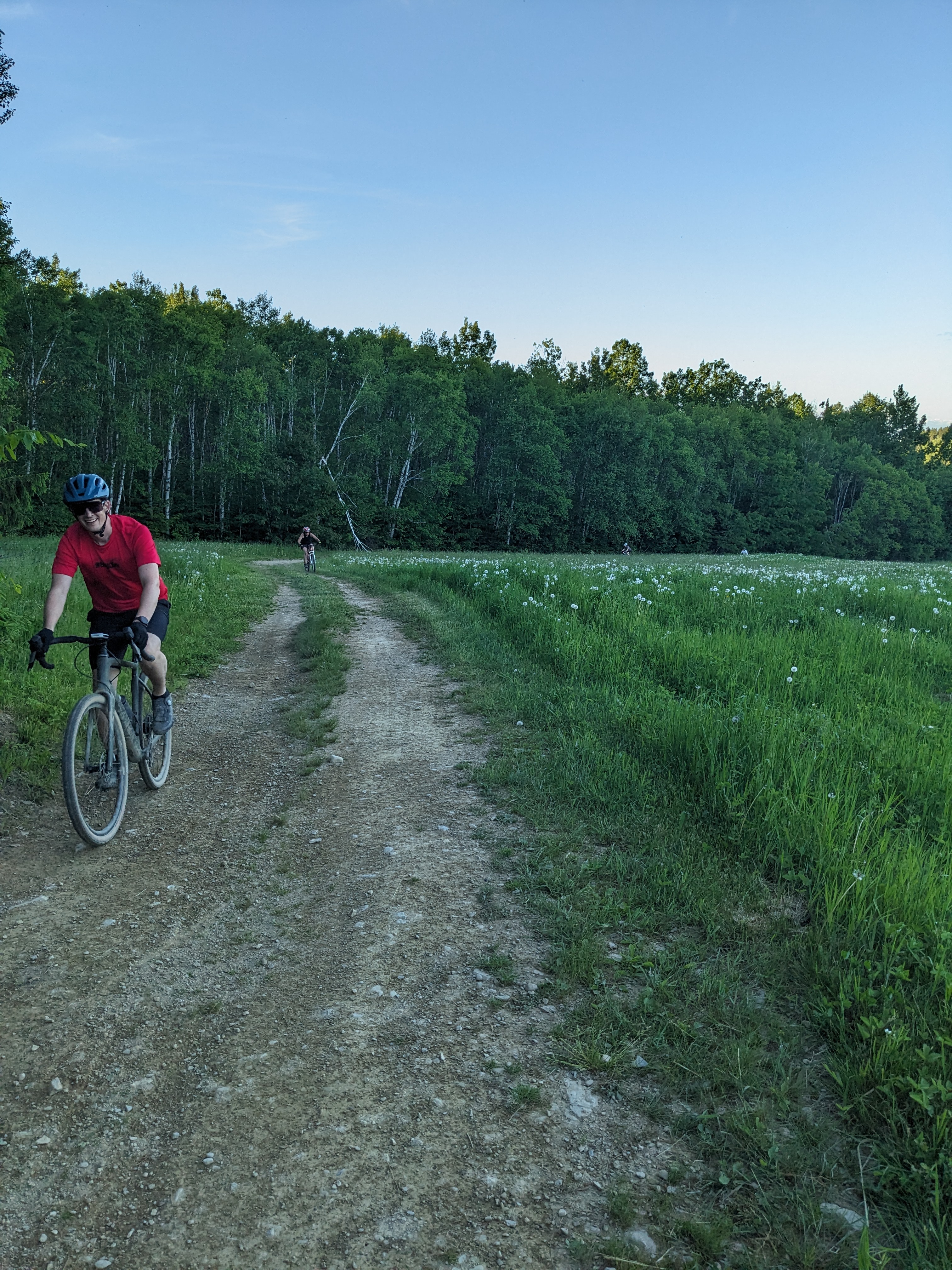 Rider smiling on a dirt path alongside a wildflower field